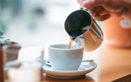 コーヒーカップにコーヒーを注いでいる写真
